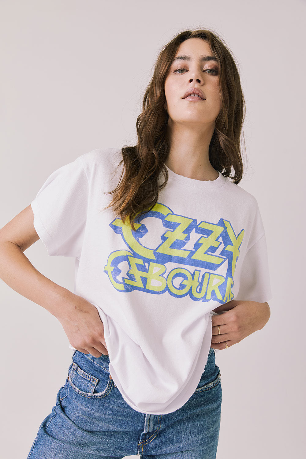 Front view of woman wearing Chaser’s white Ozzy Osbourne Tour ’86 Tee with colorful graphic design on a plain background