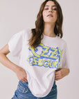 Front view of woman wearing Chaser’s white Ozzy Osbourne Tour ’86 Tee with colorful graphic design on a plain background