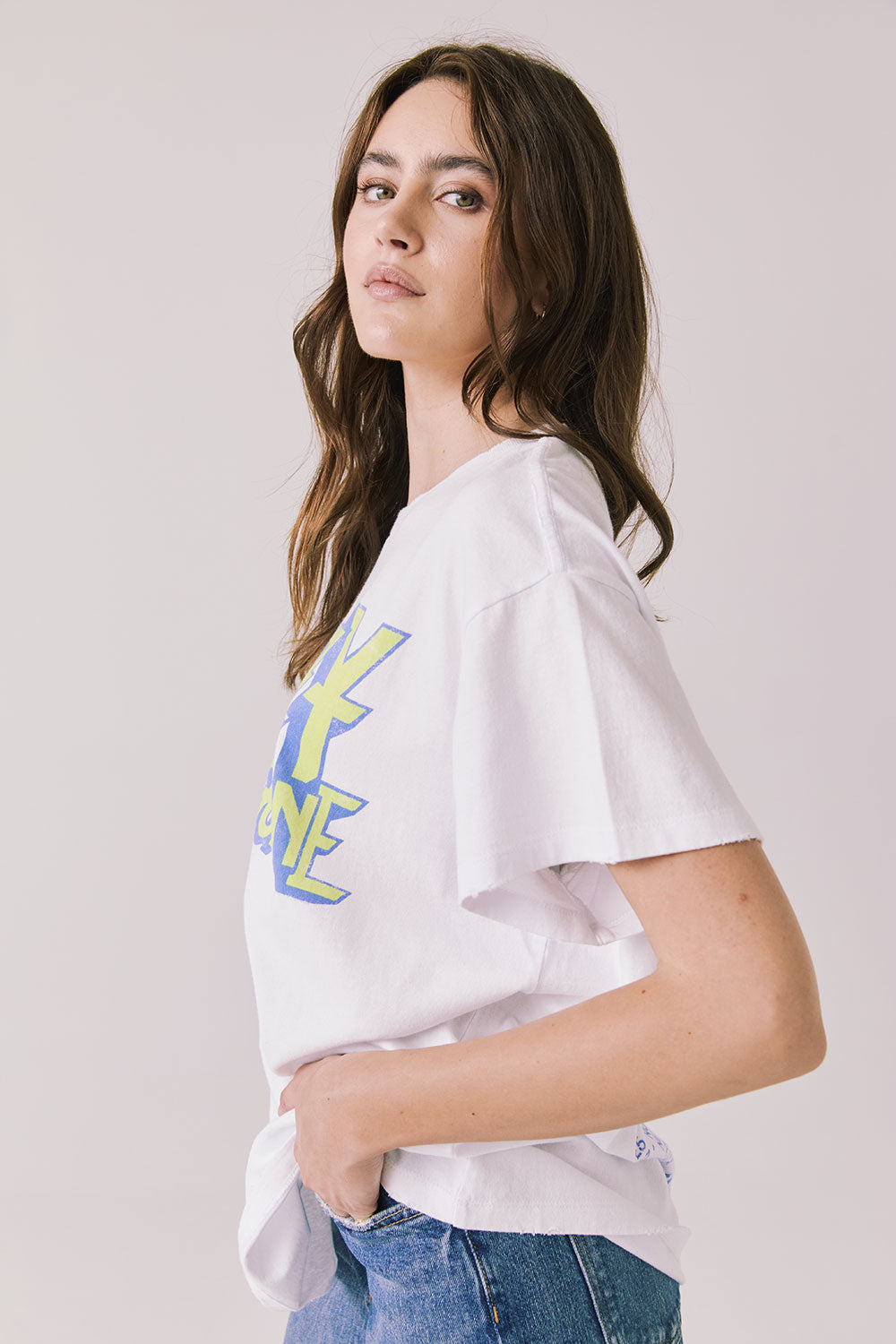 Side view of woman wearing Chaser’s white Ozzy Osbourne Tour ’86 Tee showing relaxed fit and soft fabric texture on a plain background