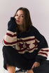 Person wearing a sweater with star pattern sitting against a plain background