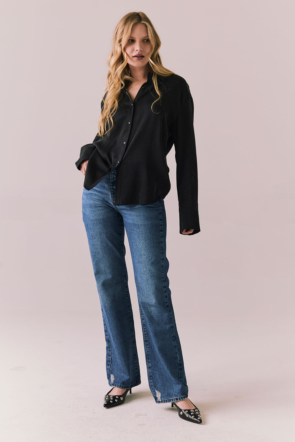 Full front view of a model wearing the Helenaa button-down shirt in True Black with collared neckline and oversized silhouette, styled with relaxed jeans against a plain backdrop.