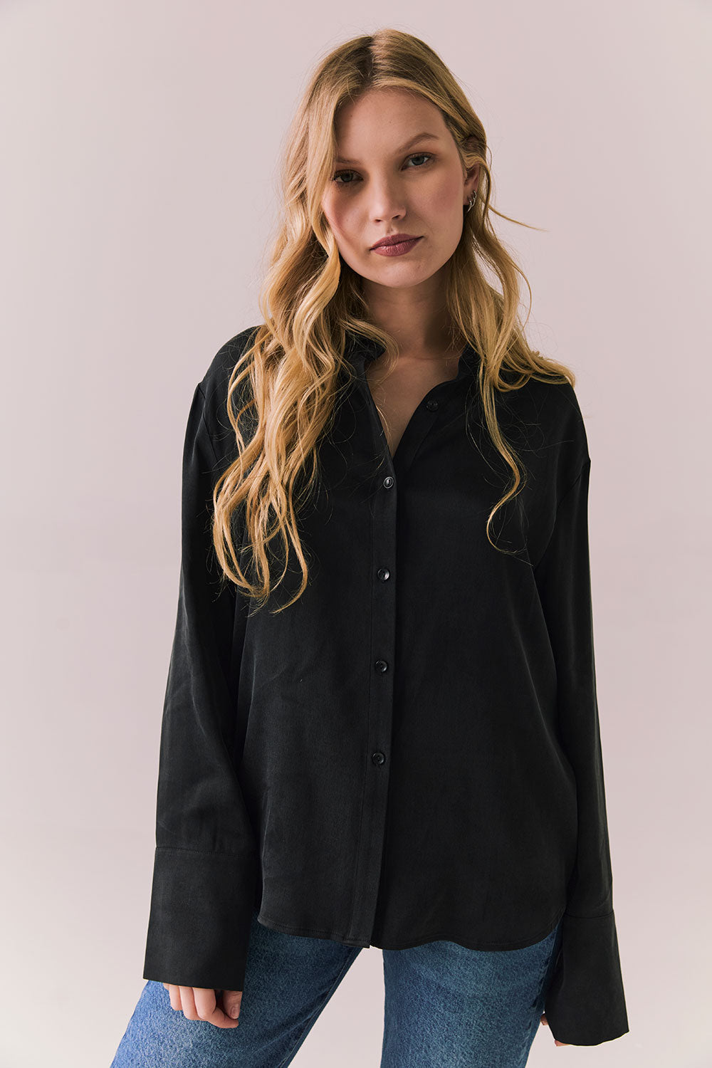 Front view of a model wearing the Helenaa button-down shirt in True Black with collared neckline and oversized silhouette, styled with relaxed jeans against a plain backdrop.