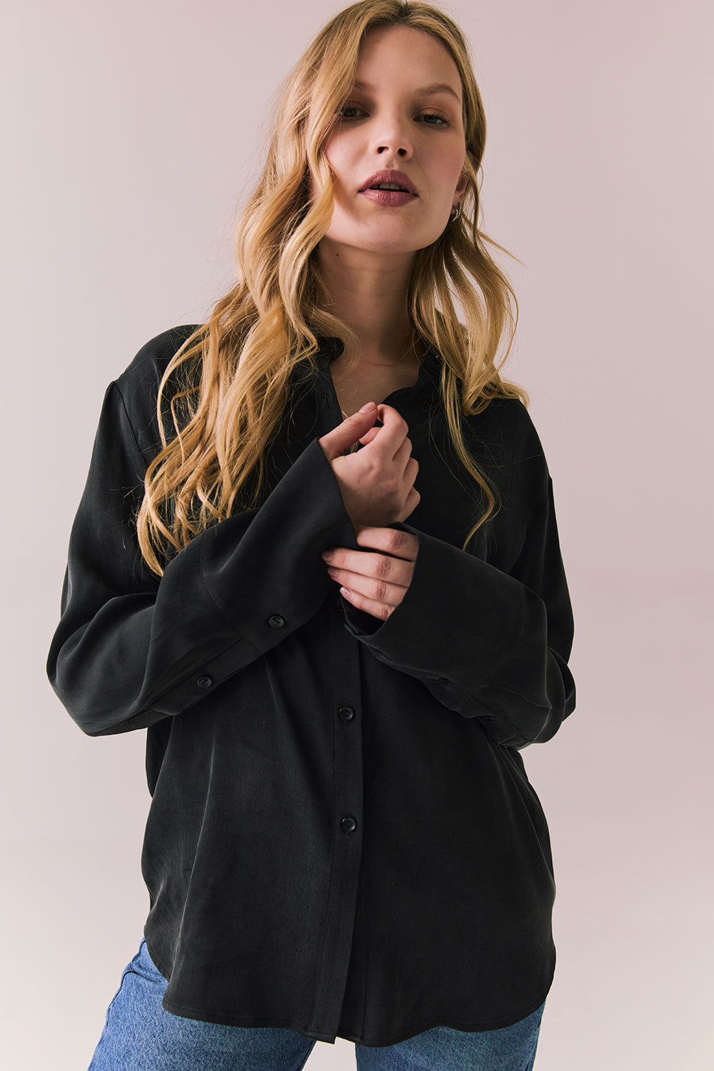Front view of a model wearing the Helenaa button-down shirt in True Black with collared neckline and oversized silhouette, styled with relaxed jeans against a plain backdrop.