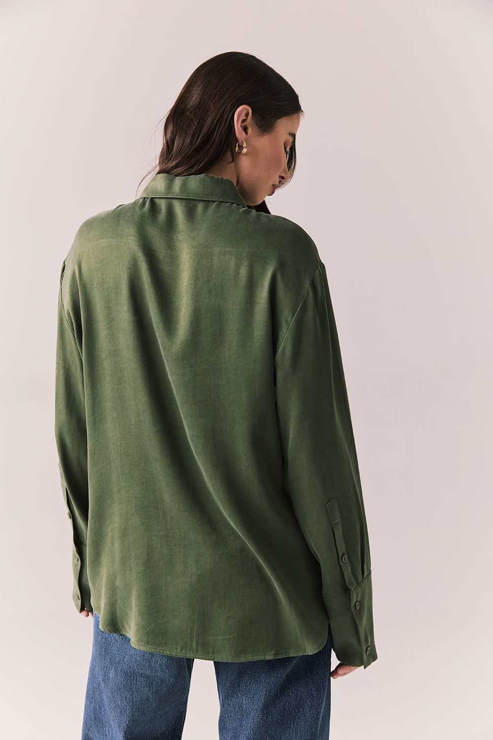 Back view of a model wearing the Helenaa button-down shirt in bronze green with collared neckline and relaxed silhouette,  against a plain background.
