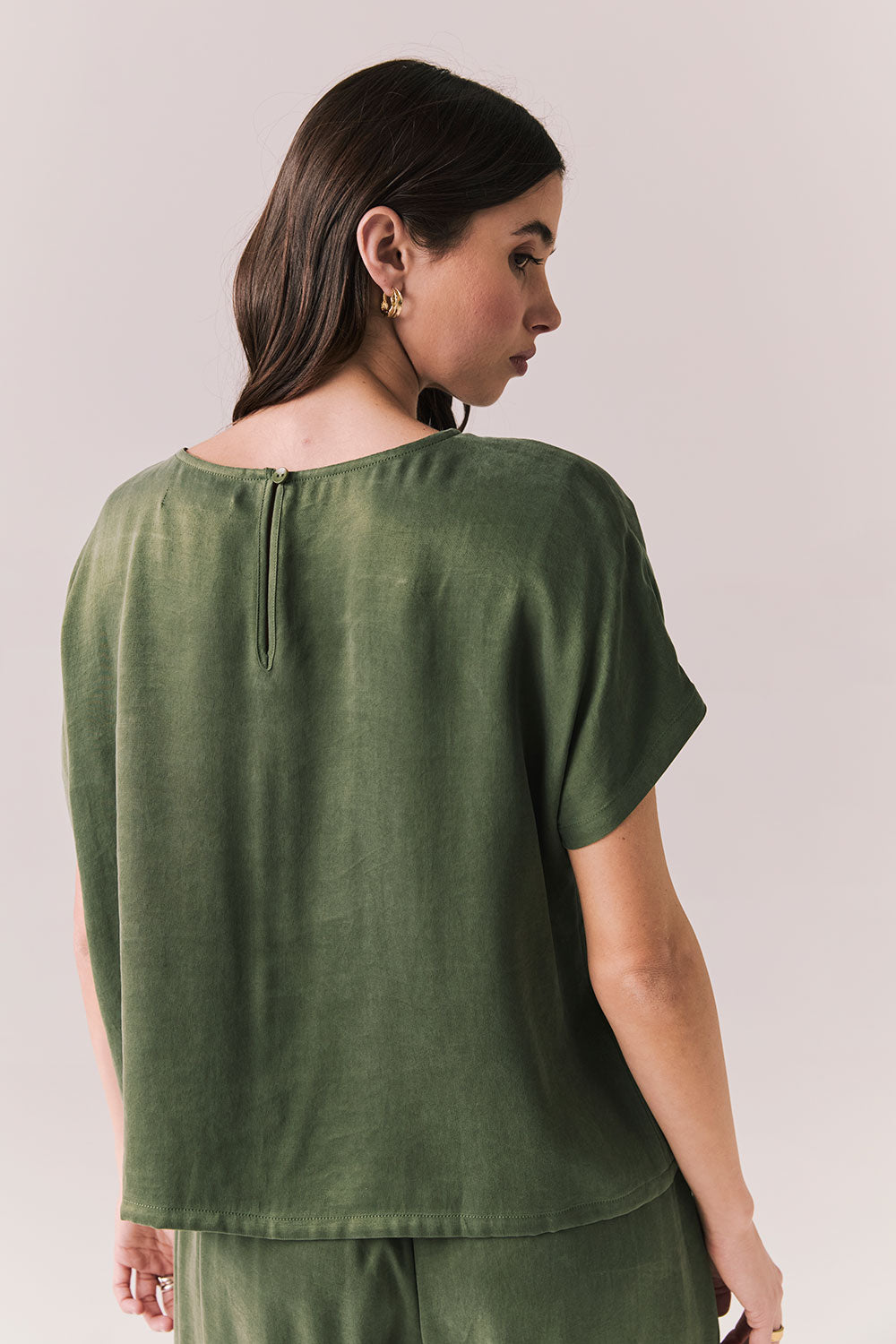 Back view of woman wearing the Davis tee in bronze green with matching Lee trousers, shot on a white background.
