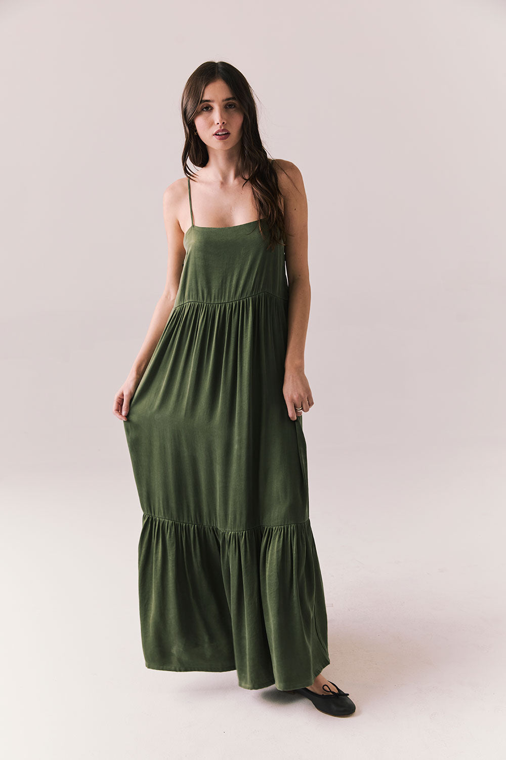 Woman wearing the Berkeley Maxi Flowy Silky Dress in Green against a white background