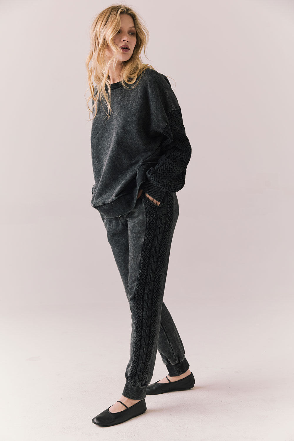 Side front view of Maritime Pullover in True Black with relaxed fit and knit texture and matching Bay Joggers against a plain background