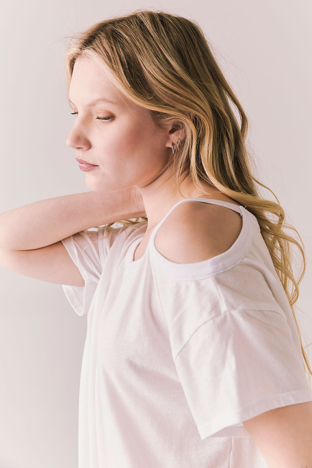 Side view of Northridge Tee in white with cold shoulder cutout against a plain background
