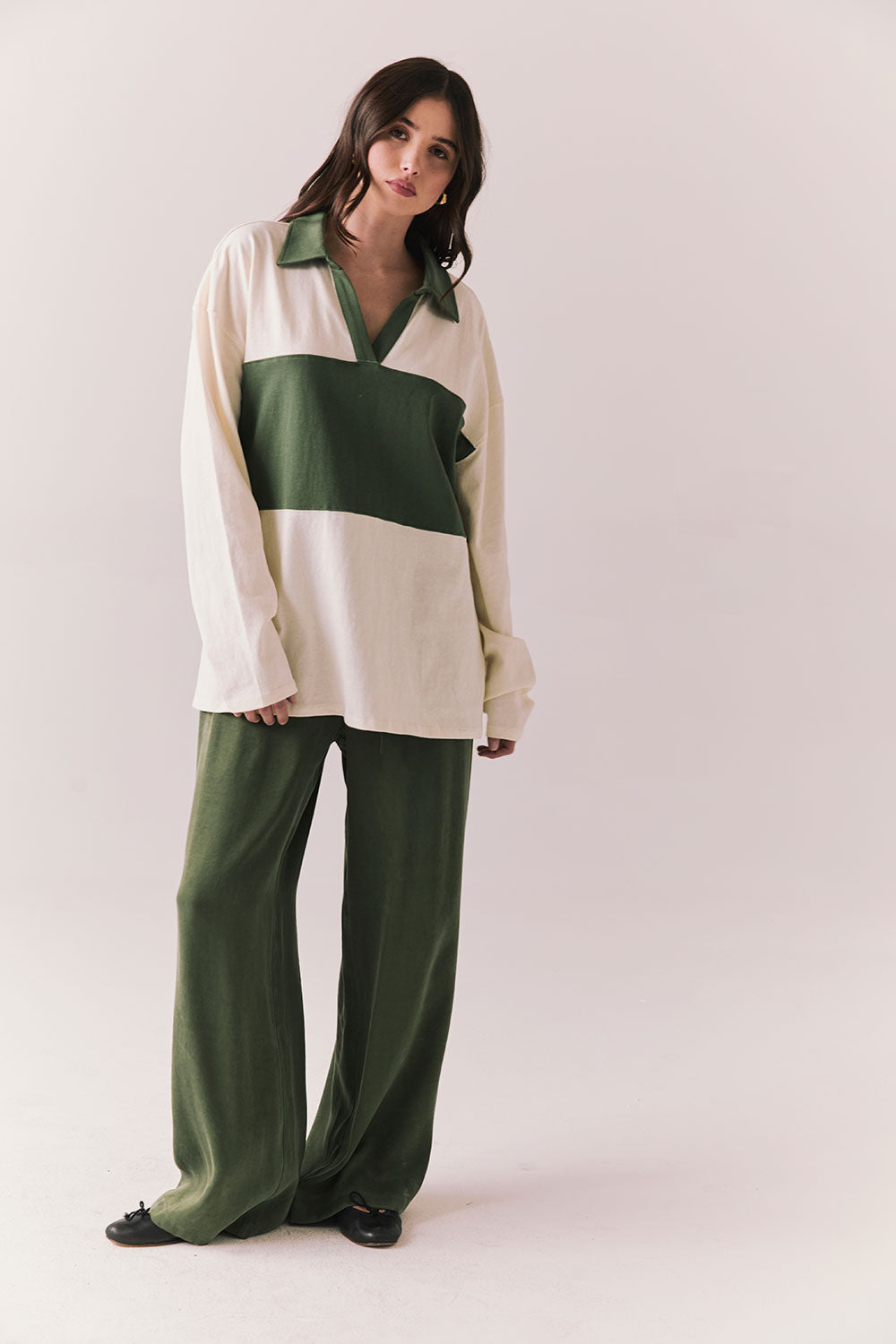 Woman wearing the color-blocked Chico Long Sleeve White and Green Rib Pullover and green pants on a white background