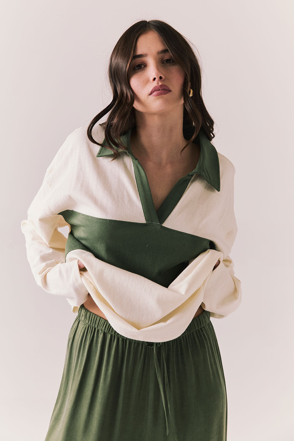 Woman wearing the color-blocked Chico Long Sleeve White and Green Rib Pullover and green pants on a white background