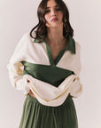Woman wearing the color-blocked Chico Long Sleeve White and Green Rib Pullover and green pants on a white background