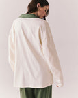 Back view of a woman wearing the color-blocked Chico Long Sleeve White and Green Rib Pullover and green pants on a white background