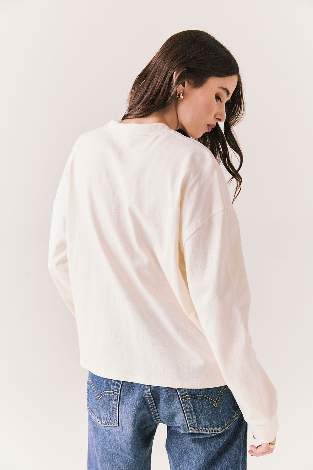 Back view of model wearing the Humboldt long sleeve in white with subtle star print and soft cotton texture and blue jeans against a white background