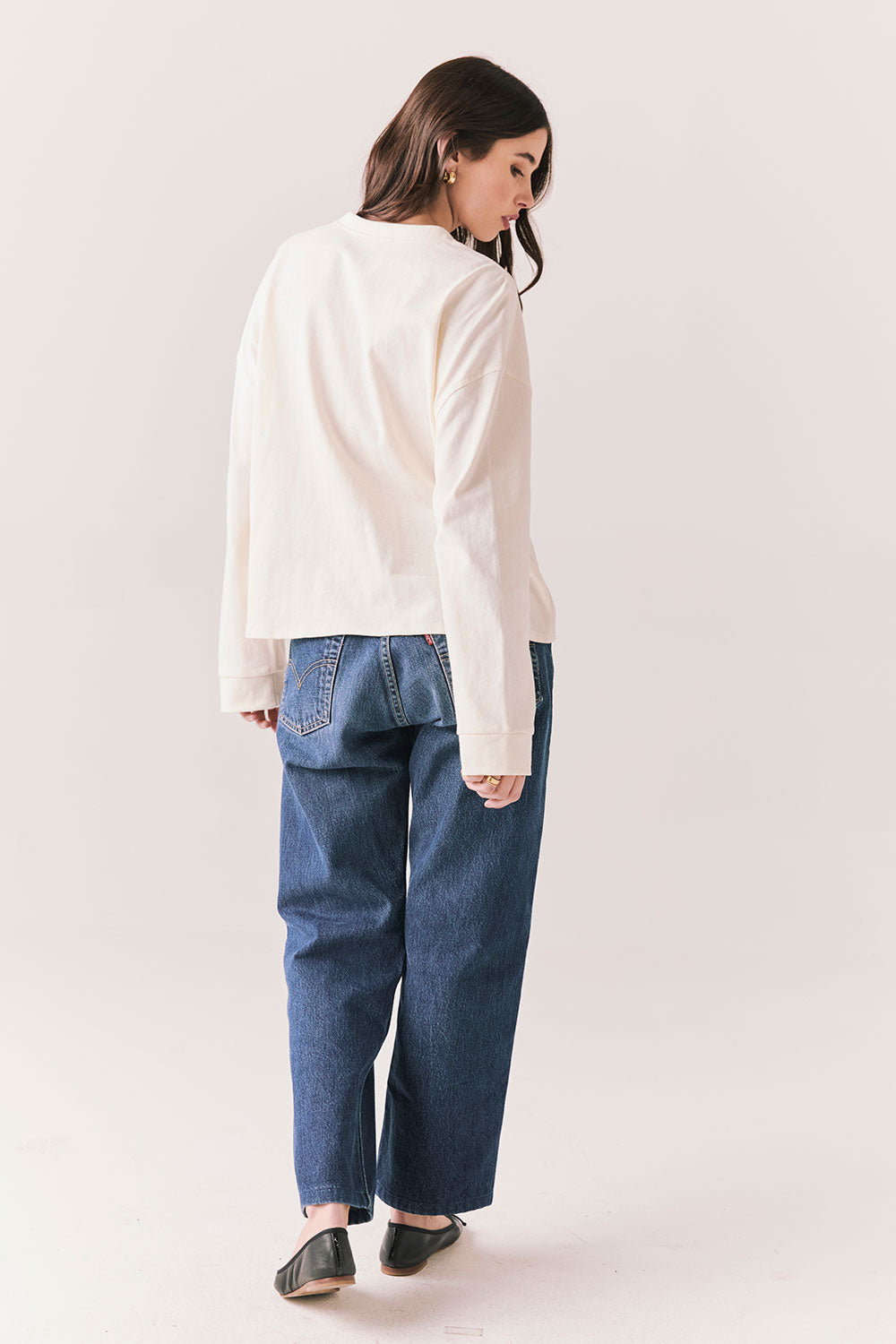 Full back view of model wearing the Humboldt long sleeve in starry white with soft cotton texture and blue jeans against a white background