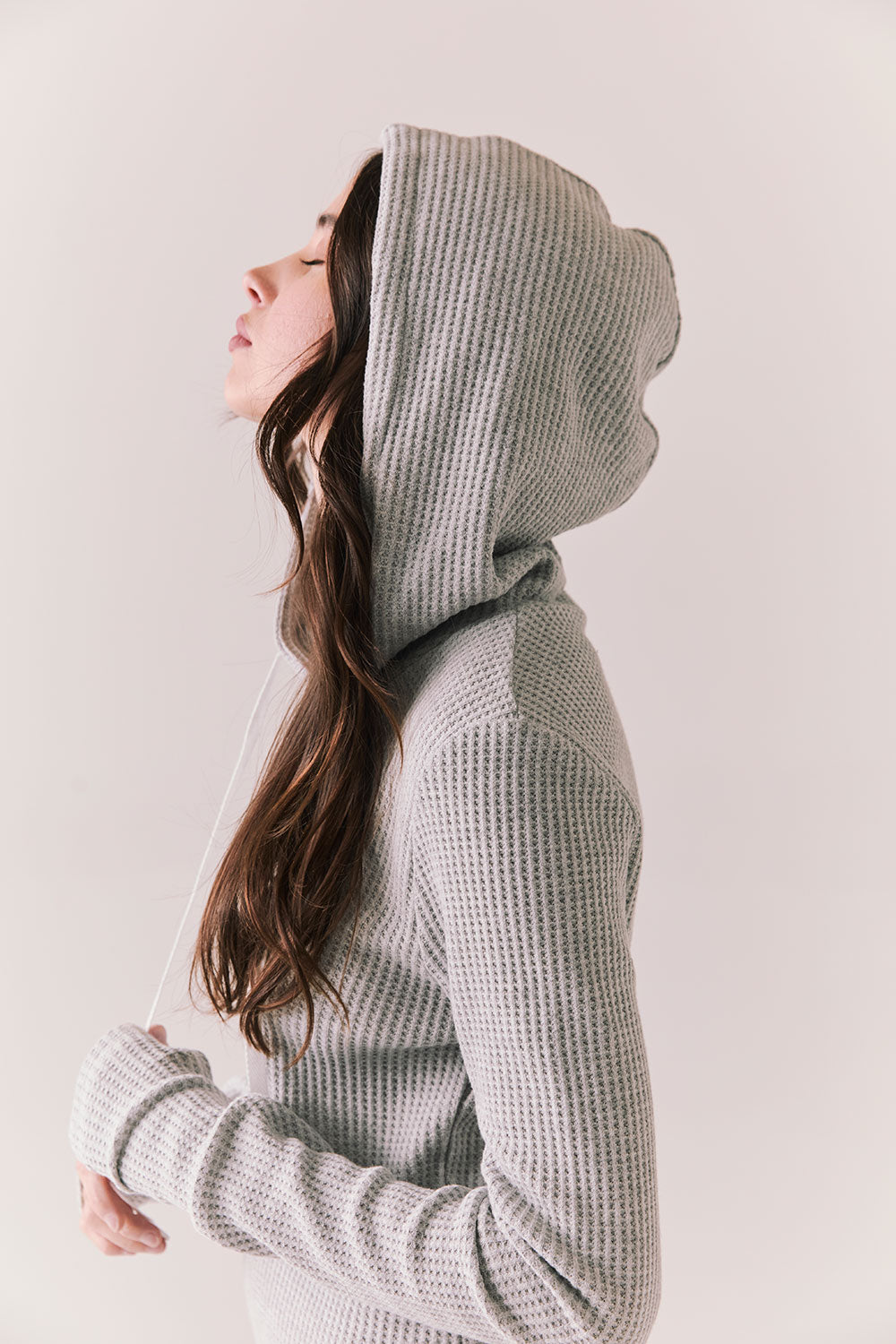 Side view of model wearing Merced Hoodie Dress in Heather Grey with hood and thermal knit texture against a plain background