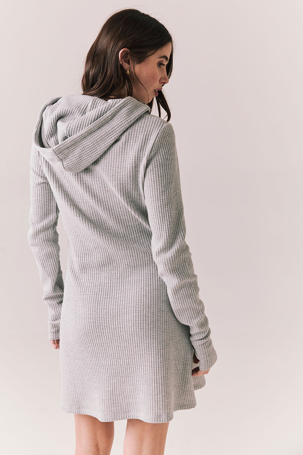 Back view of model wearing Merced Hoodie Dress in Heather Grey with hood and thermal knit texture against a plain background