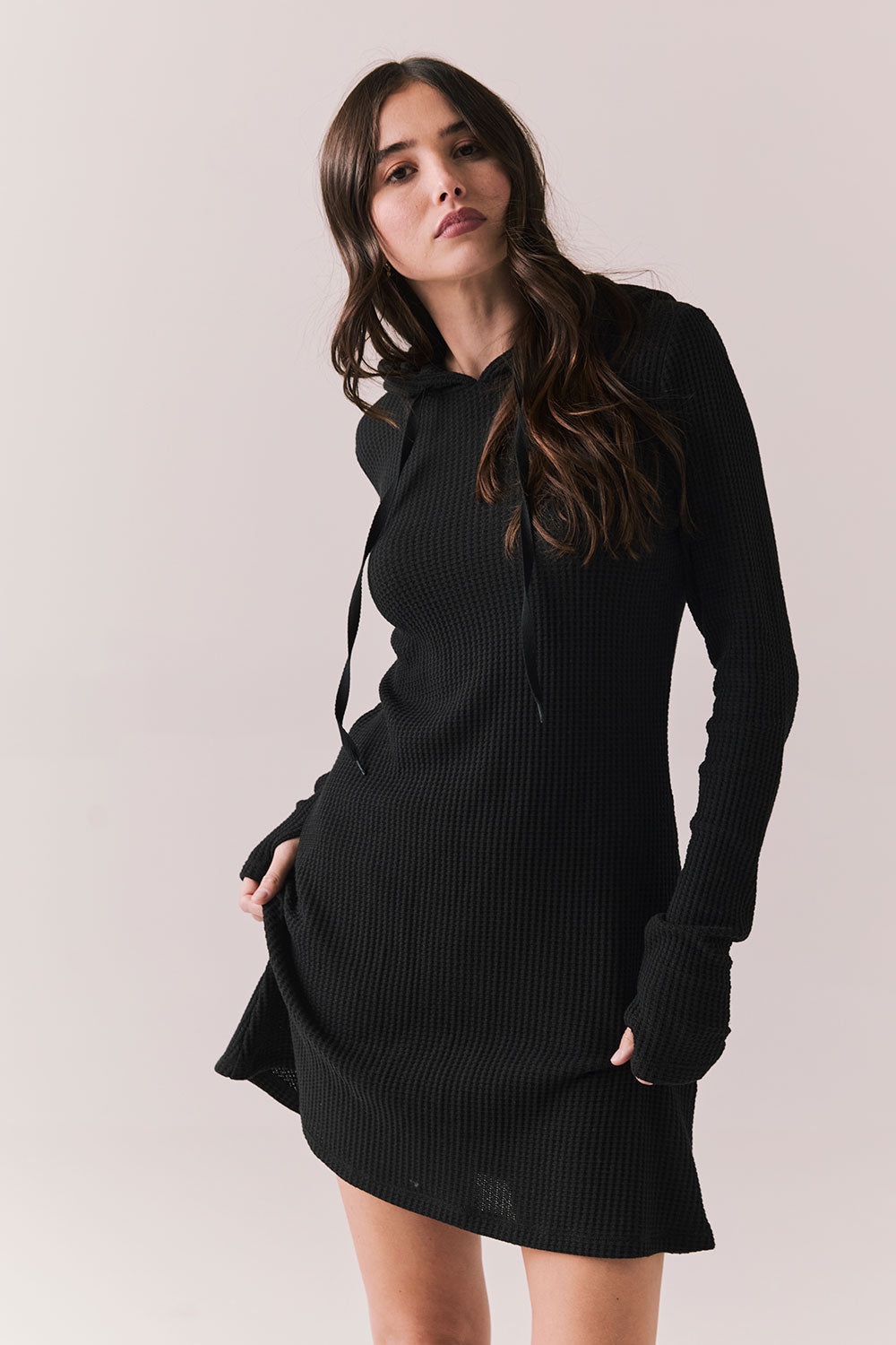 Front view of model in Merced Hoodie Dress in True Black with hood against a plain background