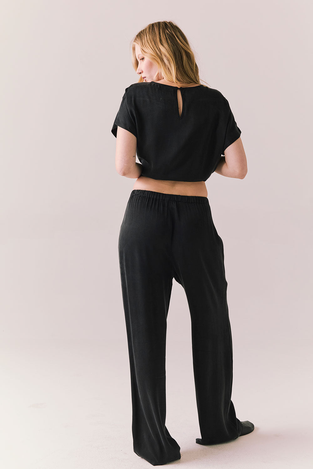 Full back view of model wearing Lee Trouser in True Black with high-rise fit and wide-leg silhouette with matching Davis top against a plain background