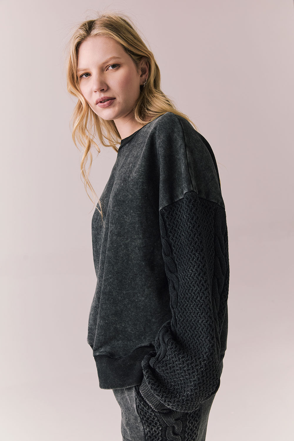 Side view of Maritime Pullover in True Black with relaxed fit and knit texture against a plain background

