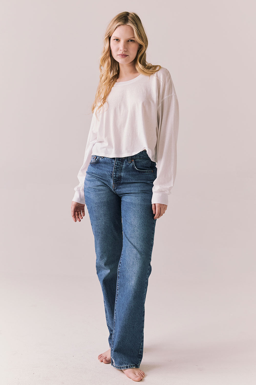 Full front view of women wearing the Hartt long sleeve in white with cotton texture and clean silhouette and blue jeans against a plain background