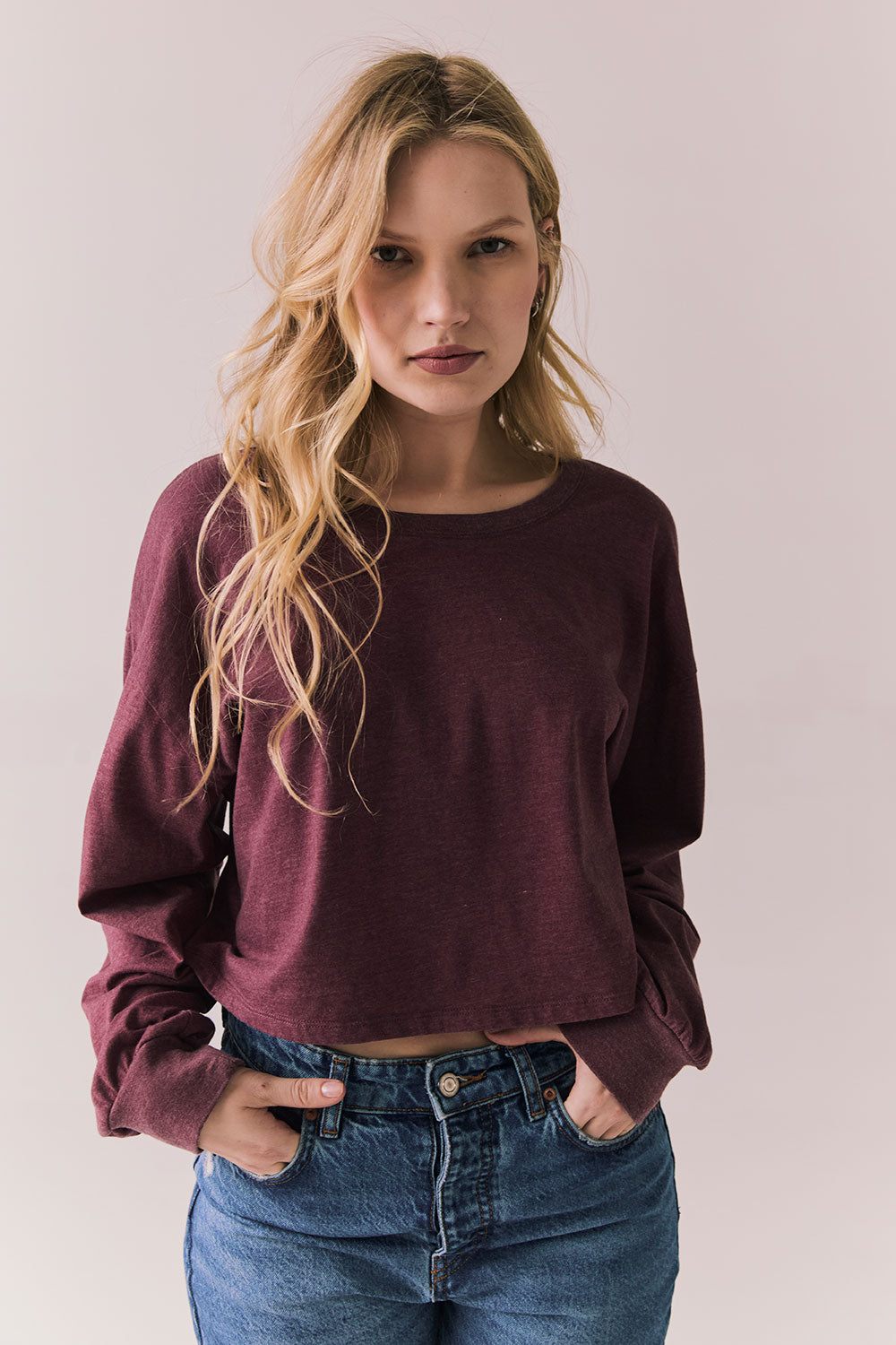 Front view of model wearing the Hartt long sleeve tee in fig (deep purple) with clean silhouette and blue jeans, against a plain background.