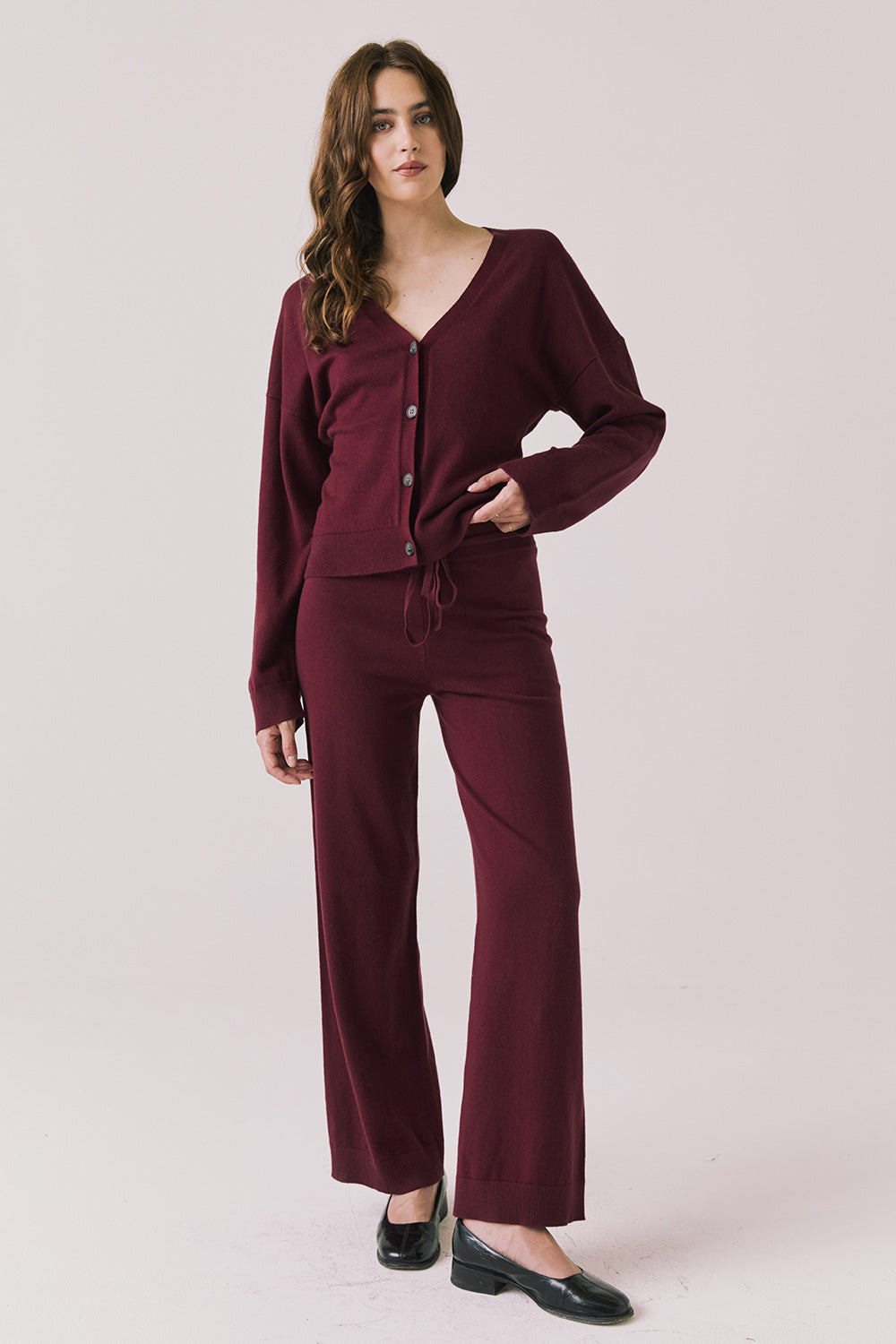 Full body view of woman wearing Chaser’s Lilou Purple Fig Joggers with matching Maison Cardigan on a plain background