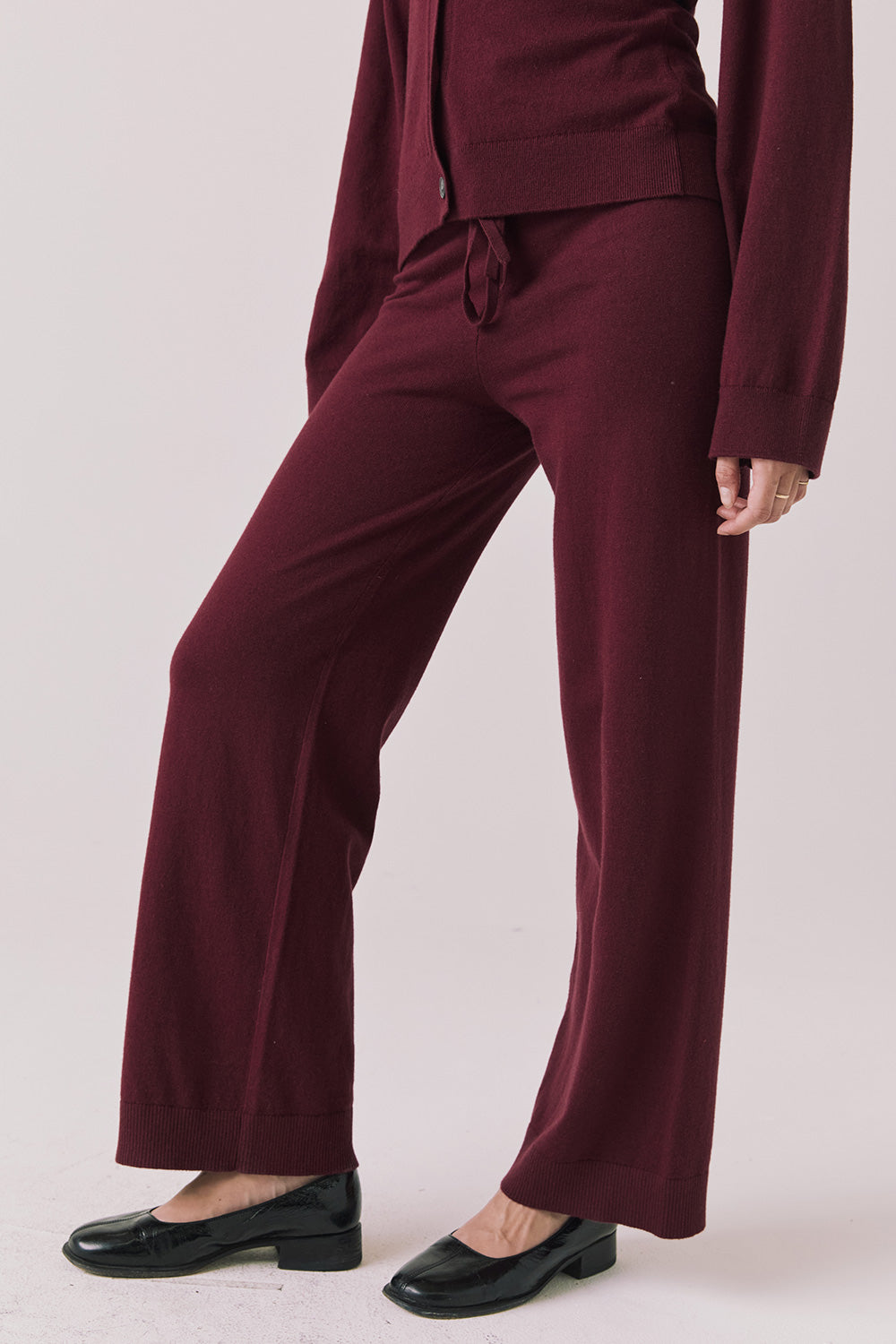 Side view of woman wearing Chaser’s Lilou Purple Fig Joggers with matching Maison Cardigan on a plain background