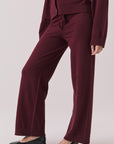 Side view of woman wearing Chaser’s Lilou Purple Fig Joggers with matching Maison Cardigan on a plain background