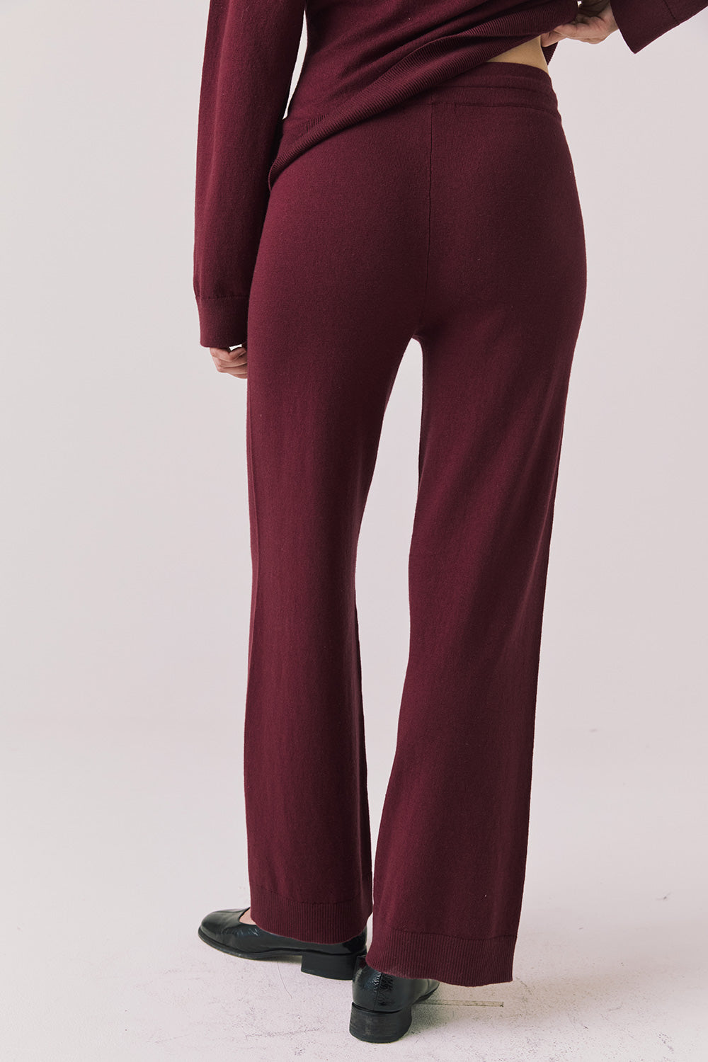 Back view of woman wearing Lilou Purple Fig Joggers on a plain background