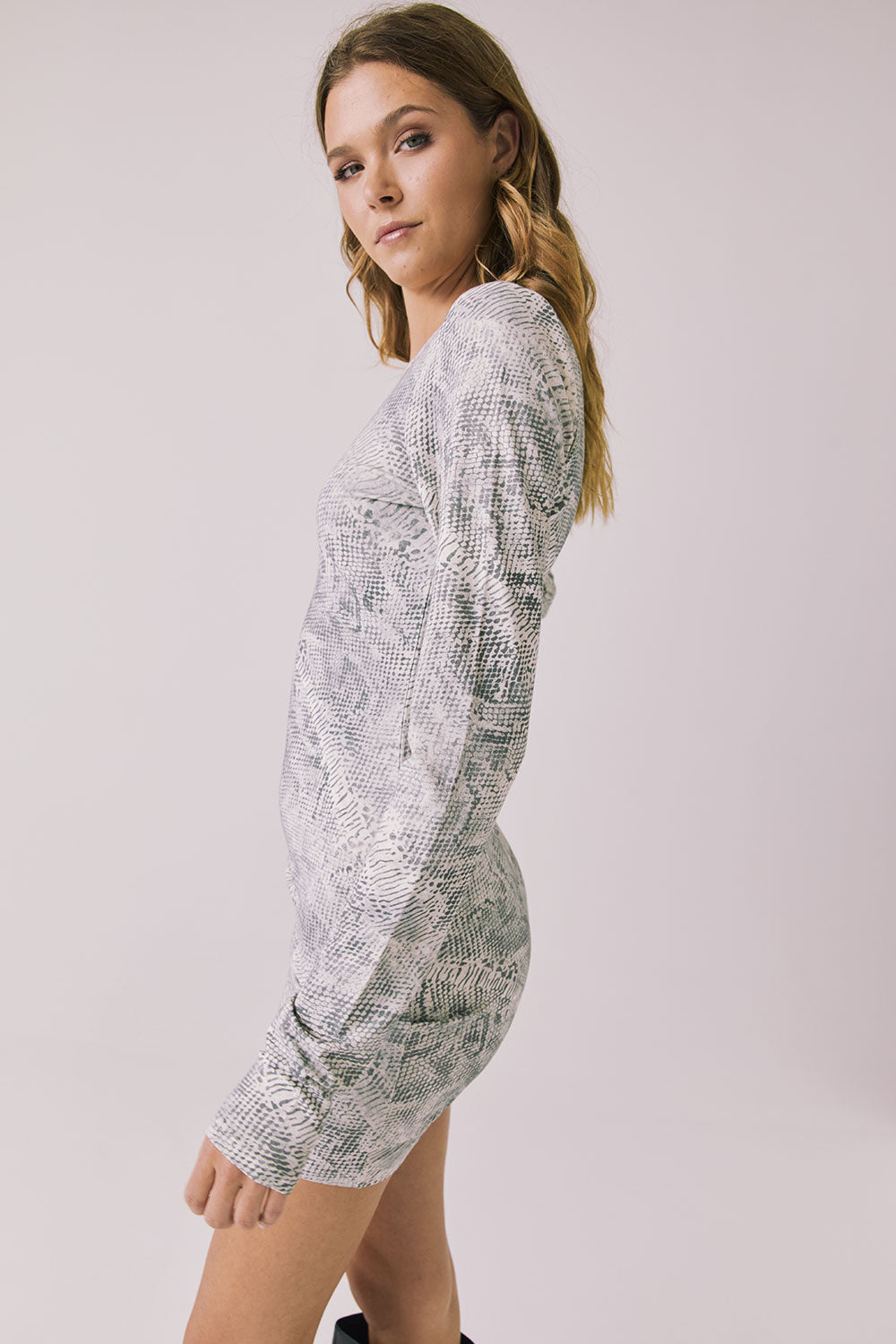 Side view of woman wearing Chaser’s Ziggy Python Print Mini Dress showing python print detail on a white background