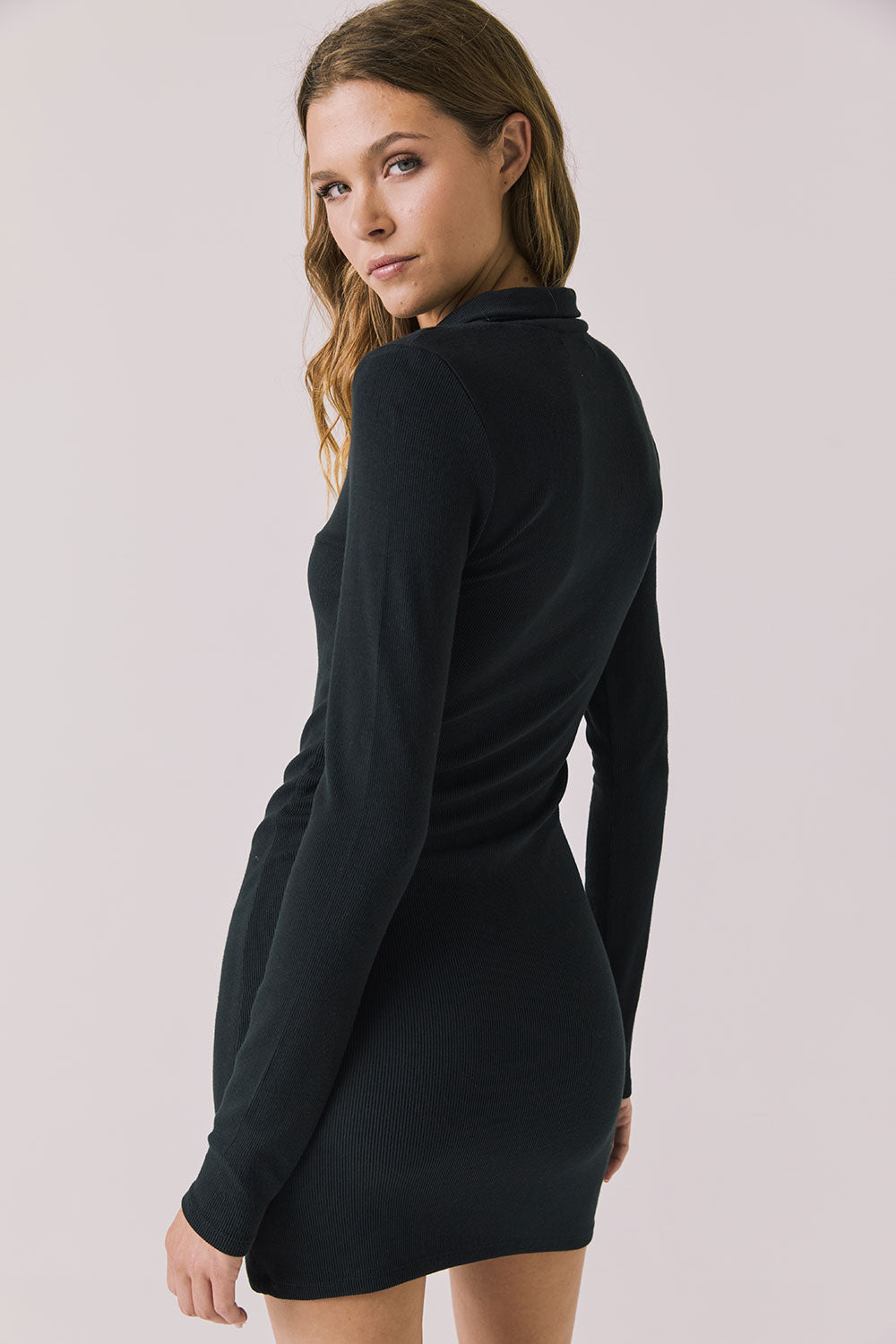 Back view of woman wearing Chaser’s Lara True Black Mini Dress with long sleeves on a white background