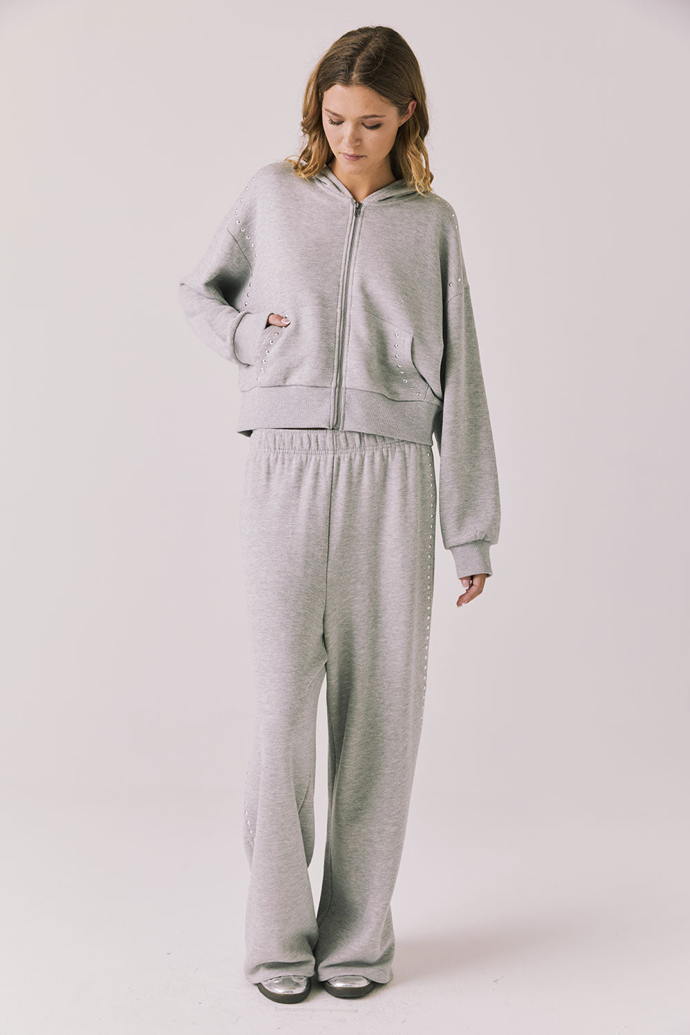 Full body view of woman wearing Chaser’s Kiki Heather Grey Zip Up Hoodie with matching Daze Heather Grey Joggers on a white background