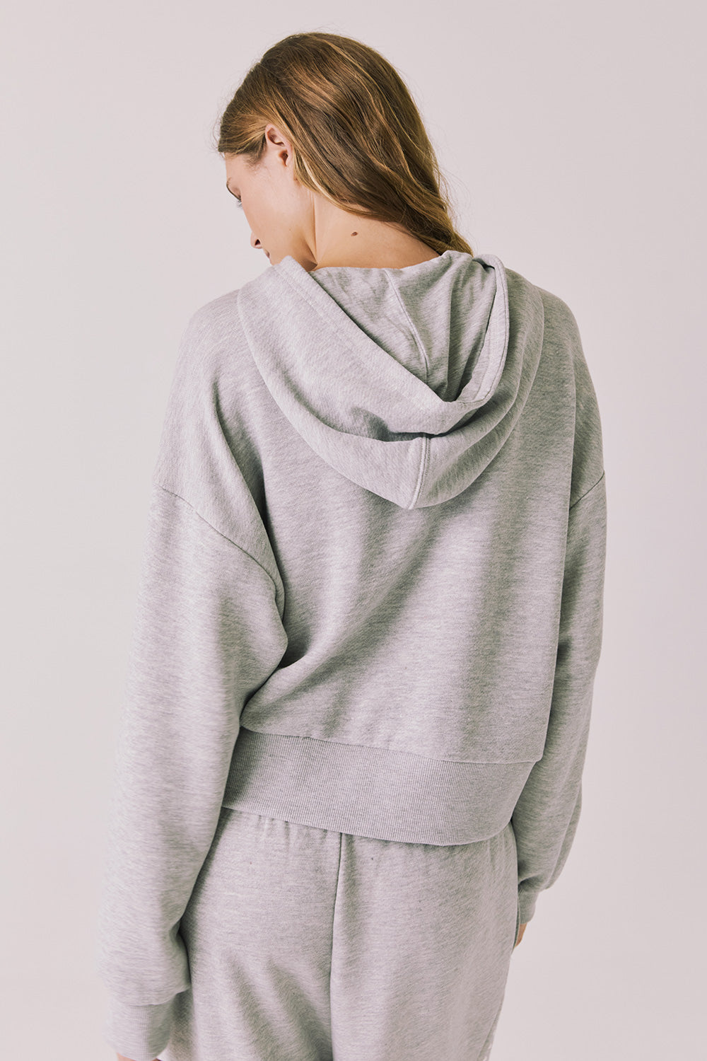 Back view of woman wearing Chaser’s Kiki Heather Grey Zip Up Hoodie on a white background