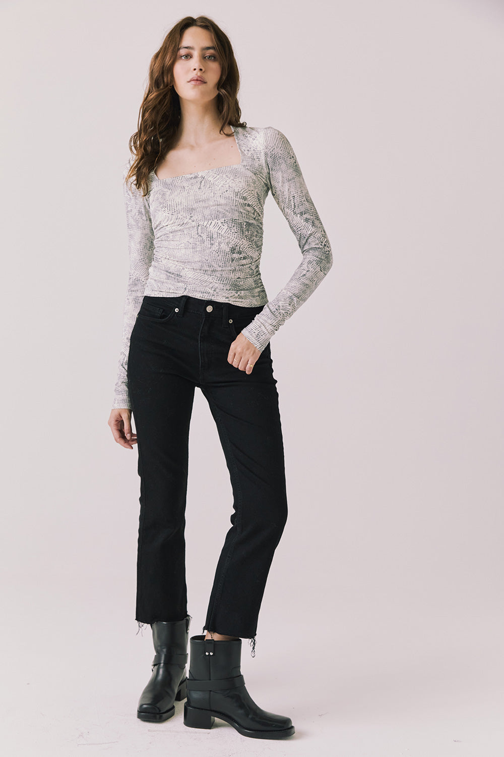 Full body view of woman wearing Chaser’s Tilly Python Print Long Sleeve with black pants and boots on a plain background