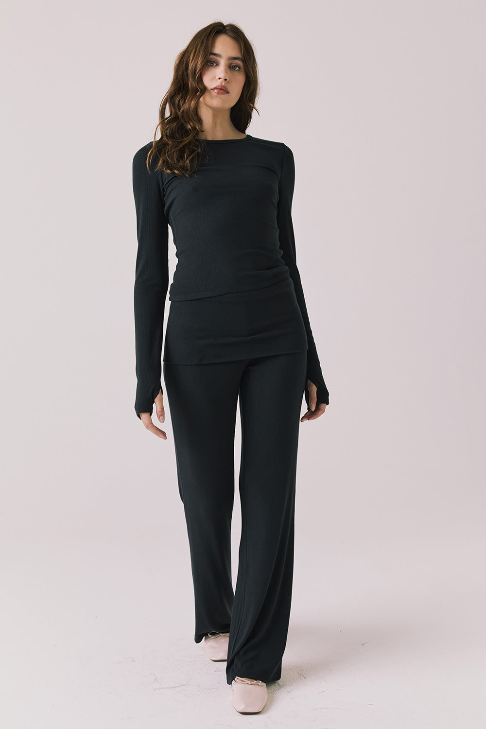 Full body view of woman wearing Chaser’s True Black Mantra Legging with matching Porta True Black Long Sleeve on a plain background