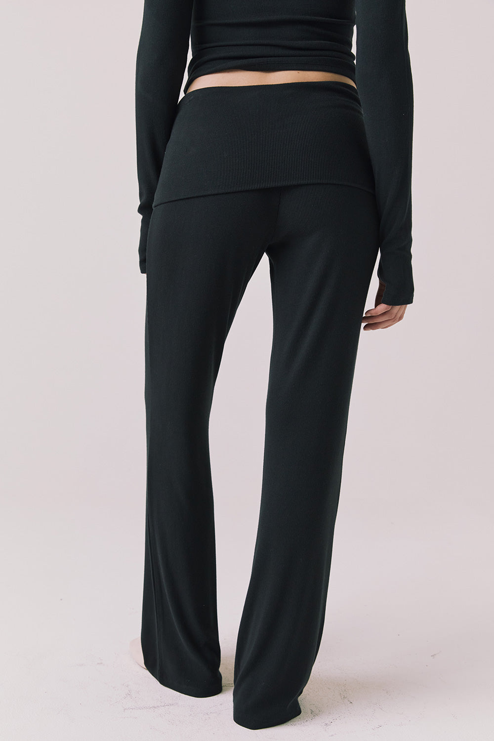 Back view of woman wearing Chaser’s True Black Mantra Legging on a plain background
