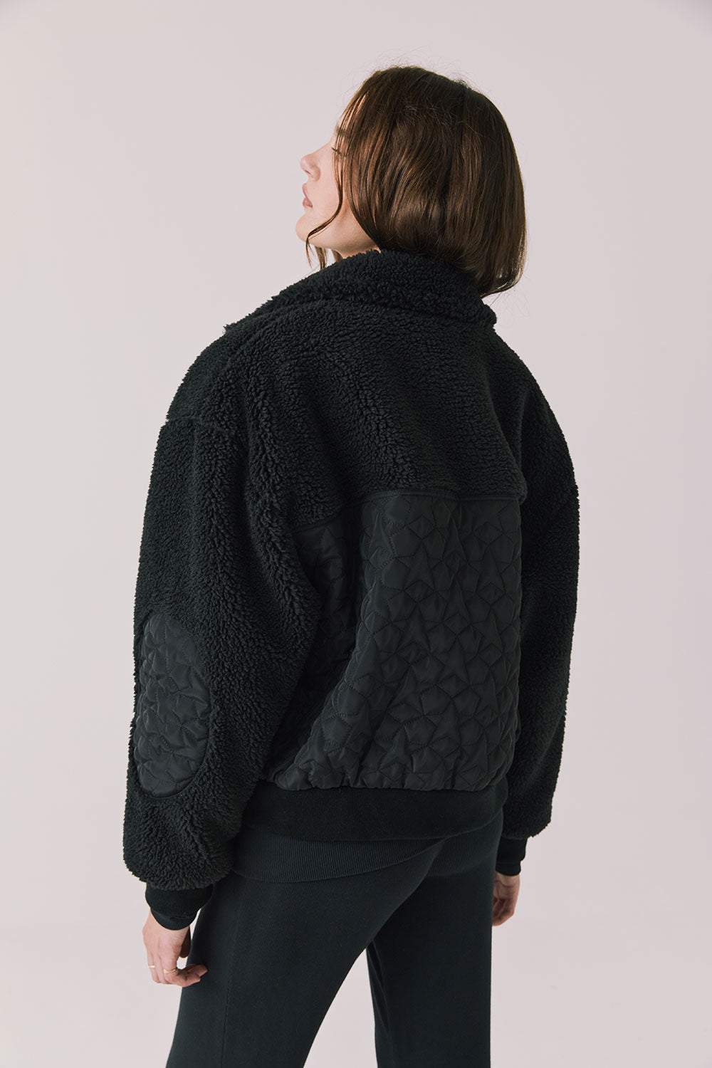 Back view of woman wearing Chaser’s Juno True Black Fleece Jacket on a plain background