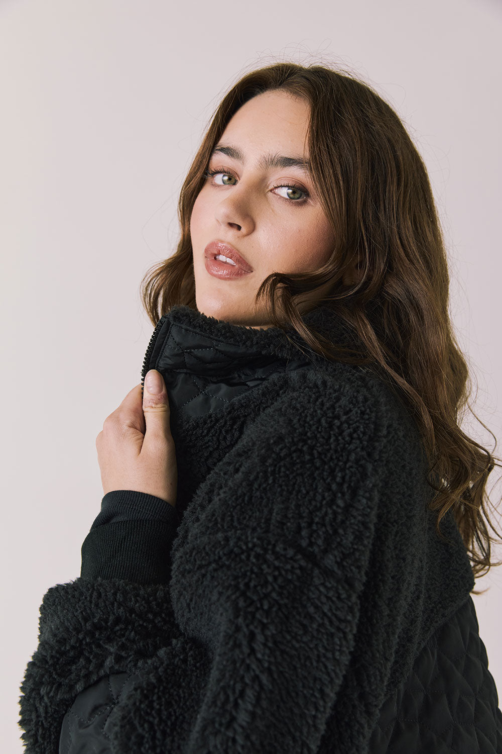 Side view of woman wearing Chaser’s Juno True Black Fleece Jacket on a plain background