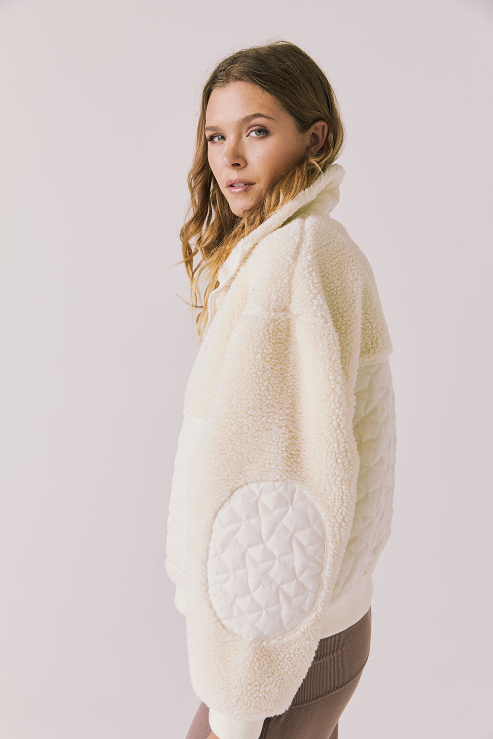 Side view of woman wearing Chaser’s Juno Warm White Fleece Jacket on a plain background
