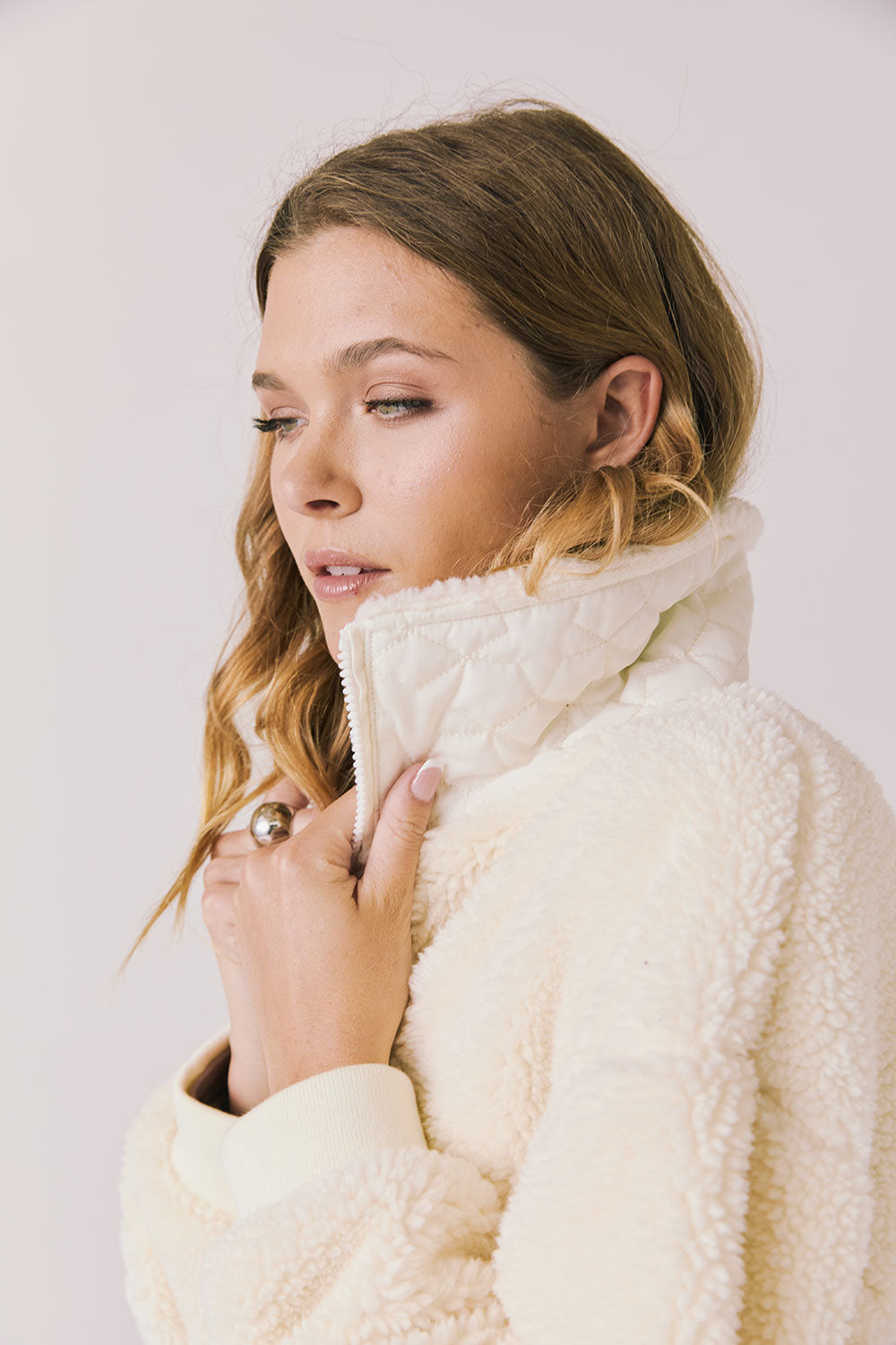 Side view of woman wearing Chaser’s Juno Warm White Fleece Jacket on a plain background