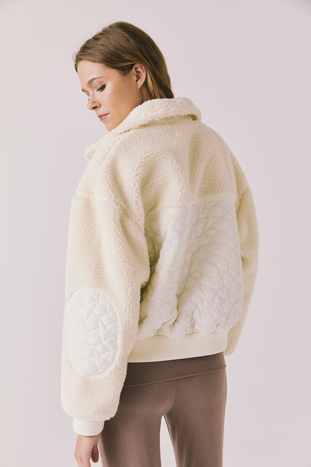Back view of woman wearing Chaser’s Juno Warm White Fleece Jacket on a plain background
