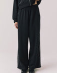 Front view of woman wearing Chaser’s Daze True Black Joggers with sequined button detailing on the pant seam on a white background