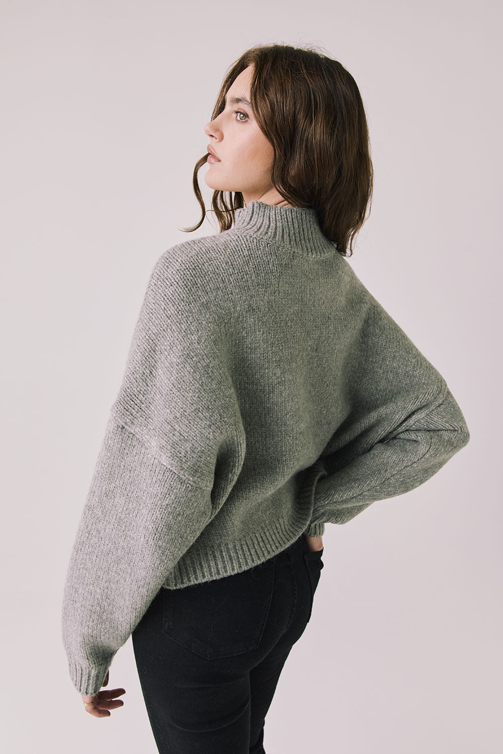 Back view of woman wearing Chaser’s Frankie Heather Grey Pullover Sweater with black pants on a white background
