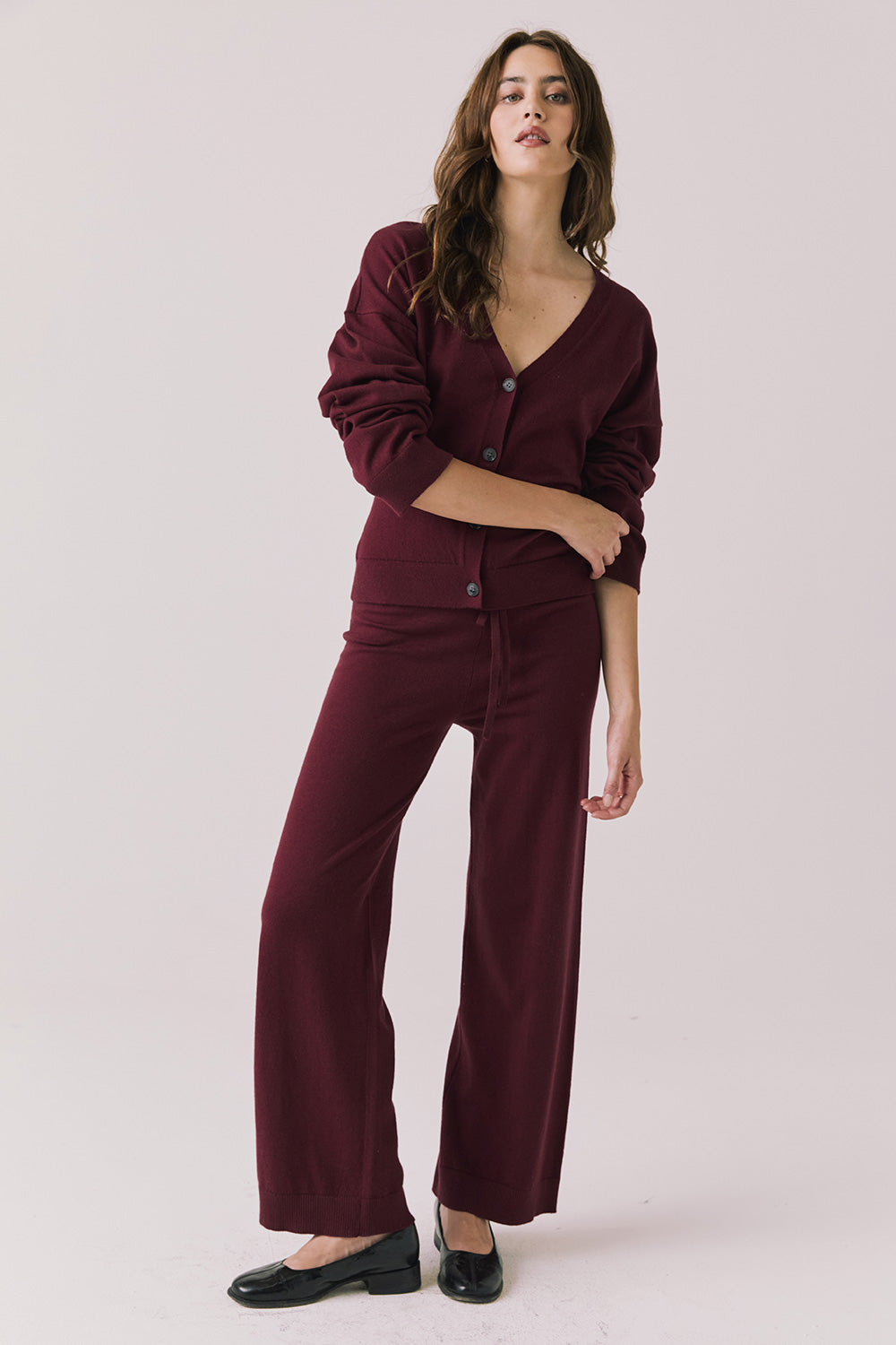 Full body view of woman wearing Chaser’s Purple Fig Maison Cardigan Sweater with matching Lilou Joggers on a white background