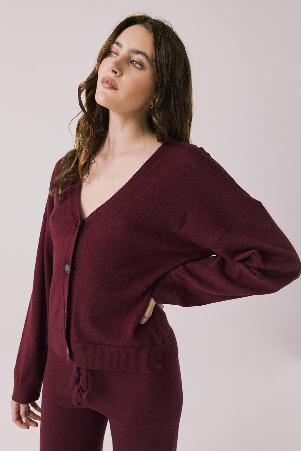 Side view of woman wearing Chaser’s Purple Fig Maison Cardigan Sweater on a white background