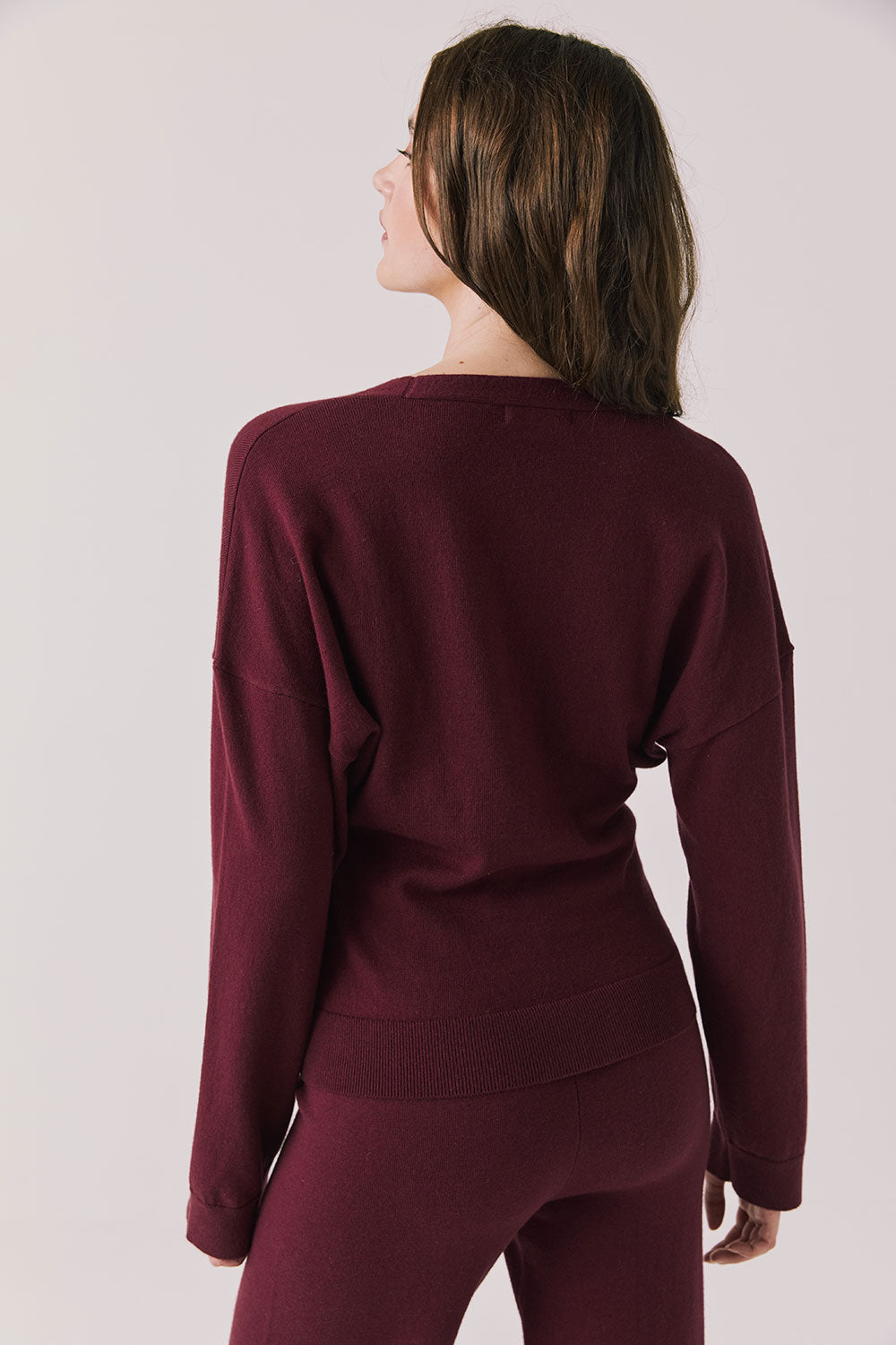 Back view of woman wearing Chaser’s Purple Fig Maison Cardigan Sweater on a white background