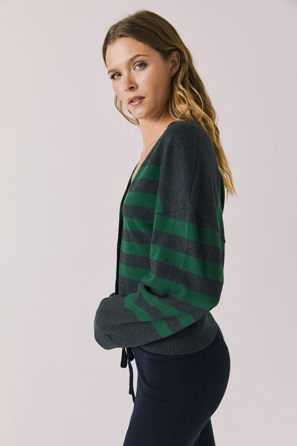 Side view of woman wearing Chaser’s Timeless Stripe Maison Cardigan Sweater on a white background