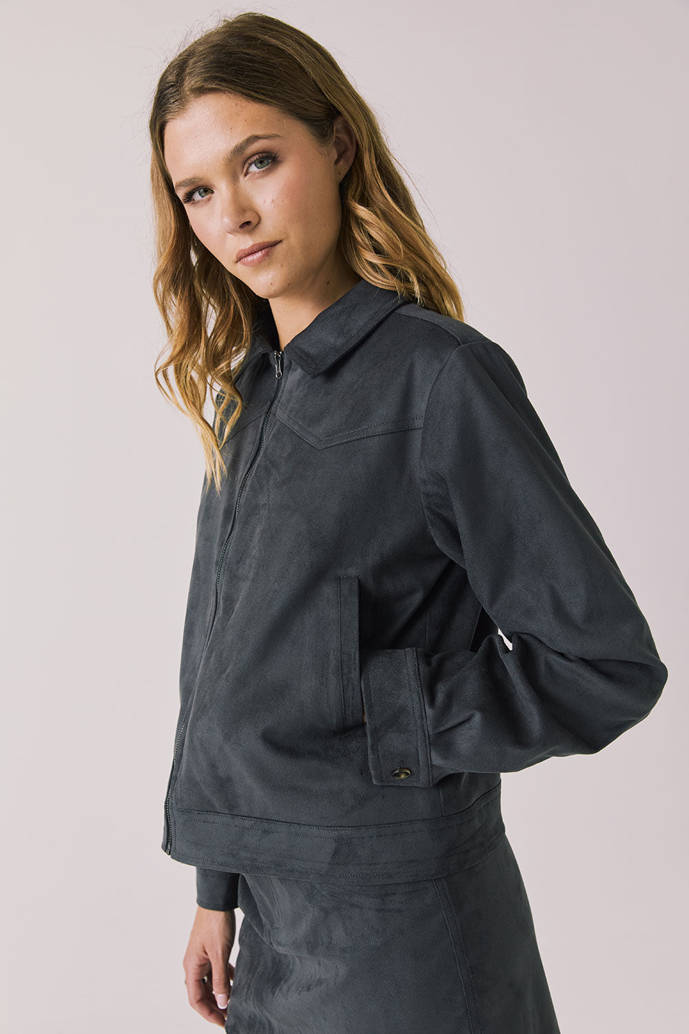 Side view of woman wearing Chaser’s Dusk True Black Jacket on a light background