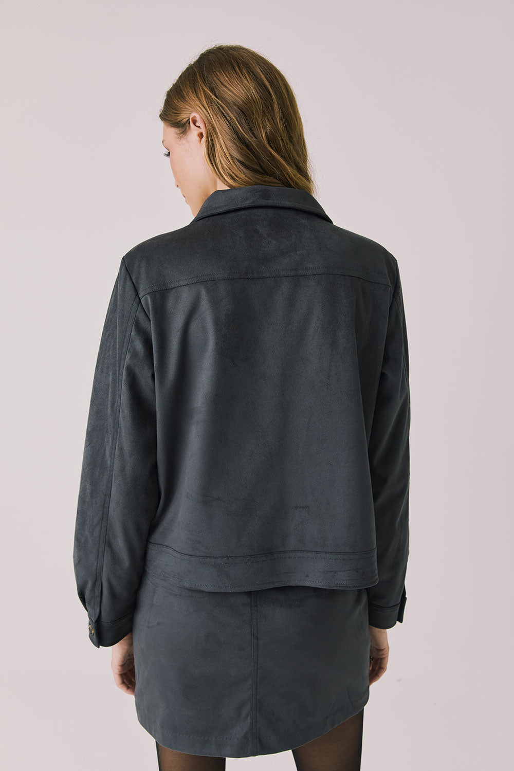 Back view of woman wearing Chaser’s Dusk True Black Jacket on a light background