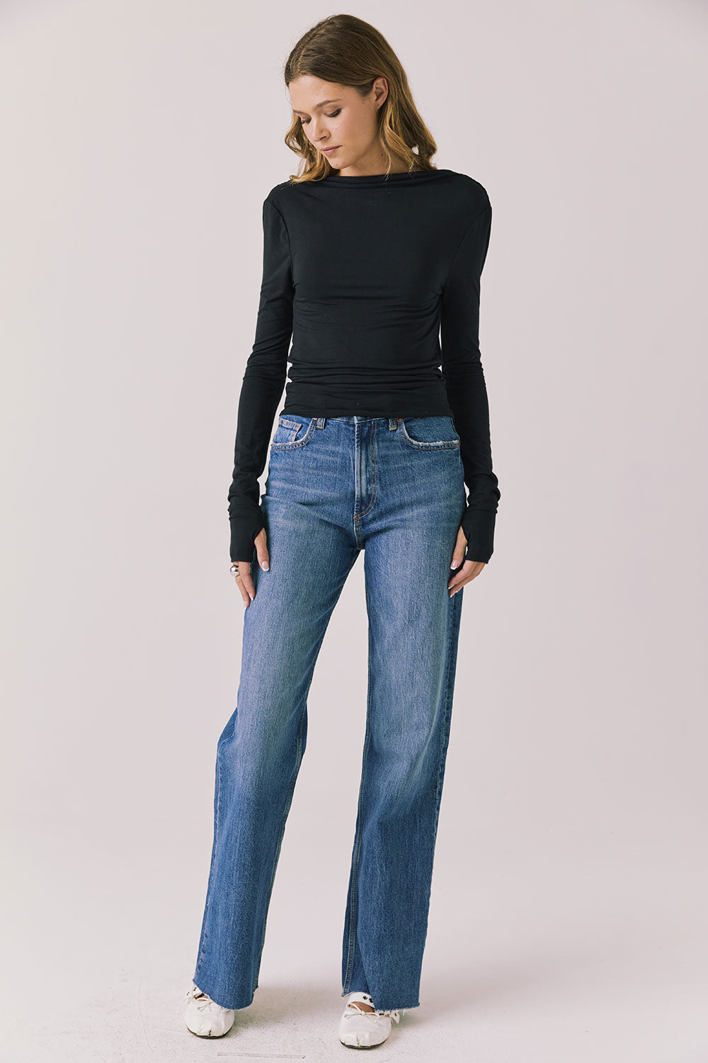 Full body view of woman wearing Chaser’s Owen True Black Long Sleeve top and blue jeans on a light gray background